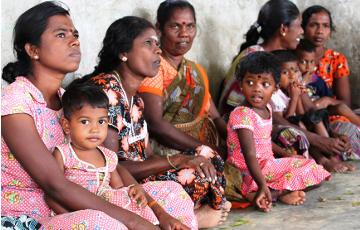 Eine Gruppe von Frauen aus Sri Lanka sitzt mit Kindern auf dem Boden