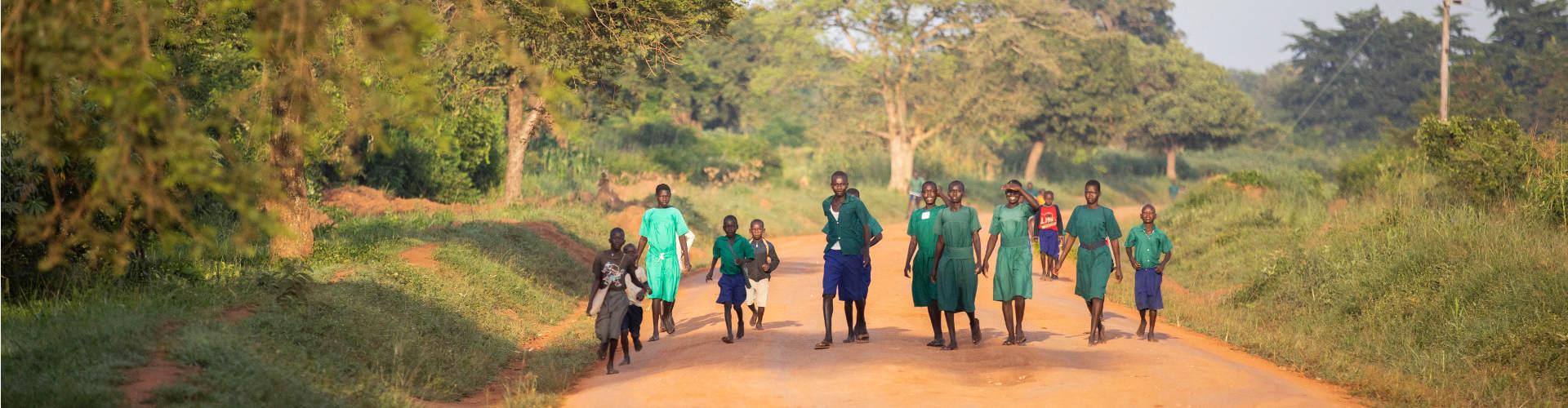 Eine Gruppe Jugendlicher geht auf einer Straße in Uganda