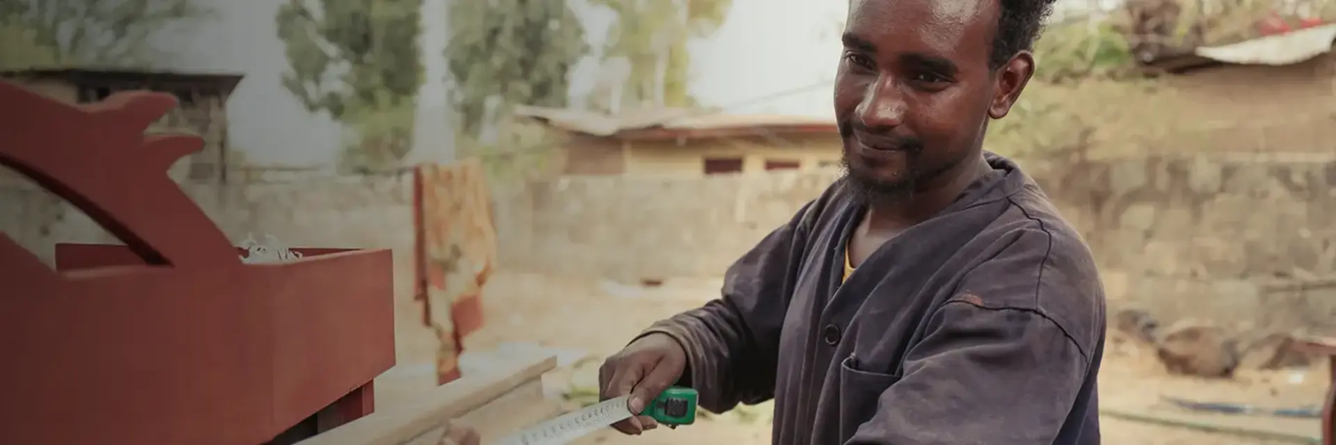 Ein junger Mann misst ein Holzstück aus.