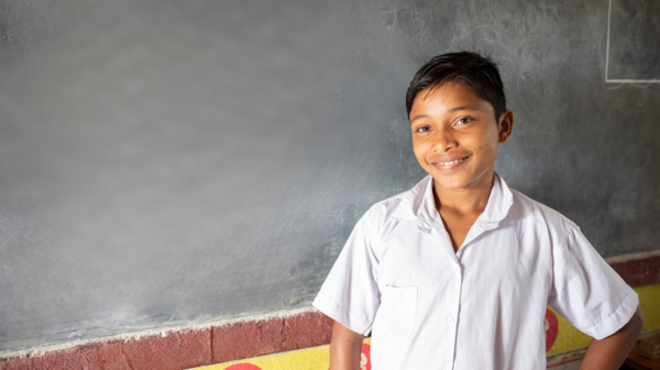 Ein Junge steht vor einer Tafel im Klassenzimmer.
