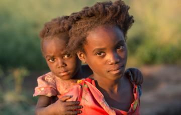 Afrikanisches Mädchen trägt ihre Schwester auf dem Rücken