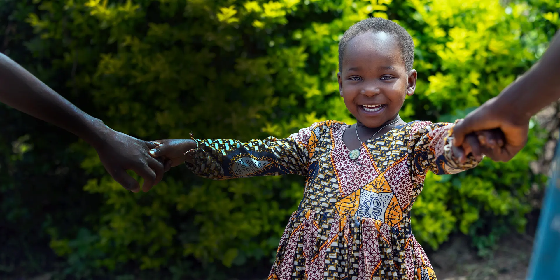 A warm welcome to our website. A child from Uganda is dancing and smiling at you in the picture.