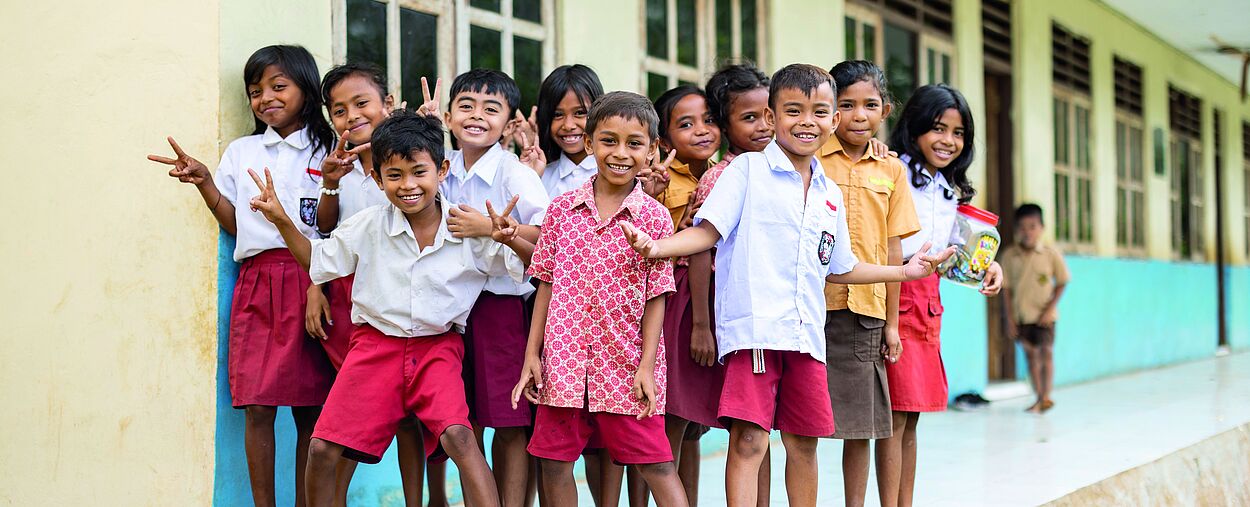 Eine Gruppe von Kindern steht posierend vor einem Schulgebäude.