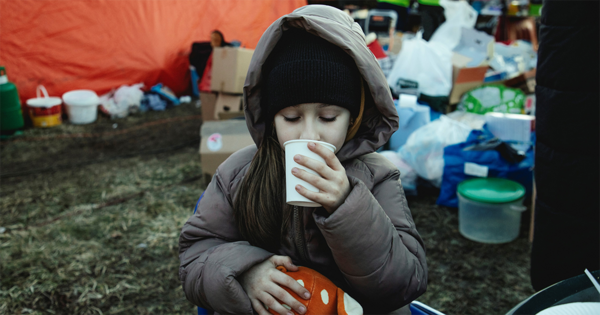Auf dem Bild trinkt ein Mädchen in einem Flüchtlingscamp aus einem Becher.