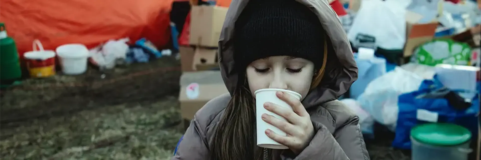 Auf dem Bild trinkt ein Mädchen in einem Flüchtlingscamp aus einem Becher.