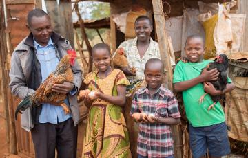 Familie steht mit Hühnern vor einem Stall in Kenia