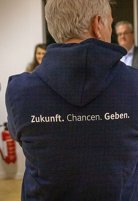 Auf dem Bild ist ein Pullover mit unserem Claim "Zukunft. Chancen. Geben." zu sehen.