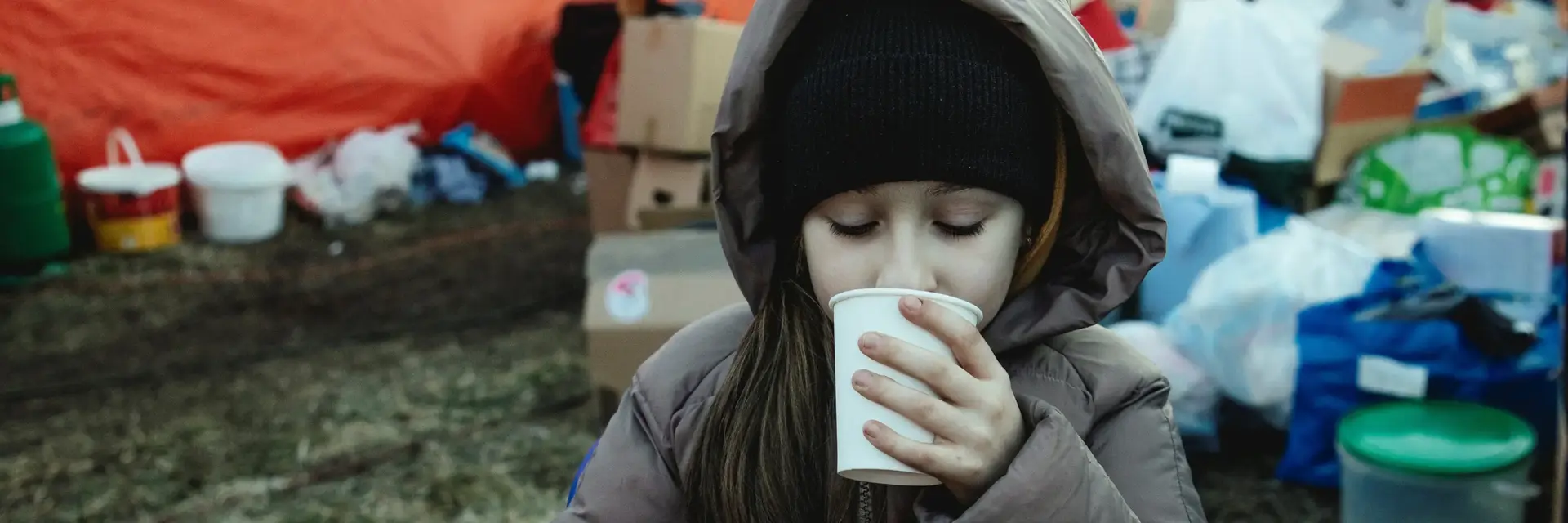 Auf dem Bild trinkt ein Mädchen in einem Flüchtlingscamp aus einem Becher.