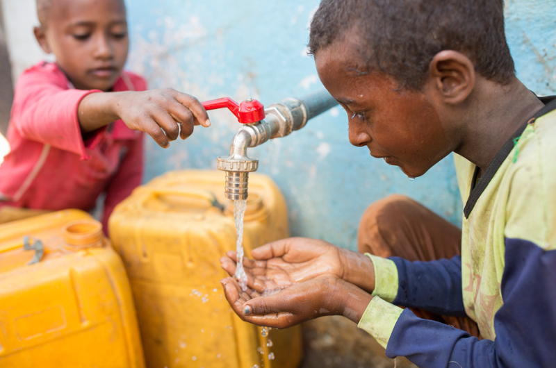 Zwei Jungen aus Äthiopien füllen Wasser in Kanister
