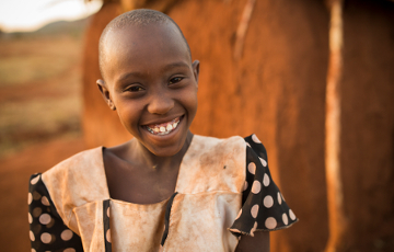 Mädchen steht vor einer Hütte in Kenia