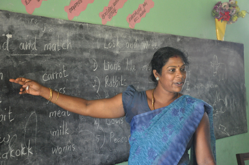 Lehrerin aus Sri Lanka zeigt etwas an der Tafel 